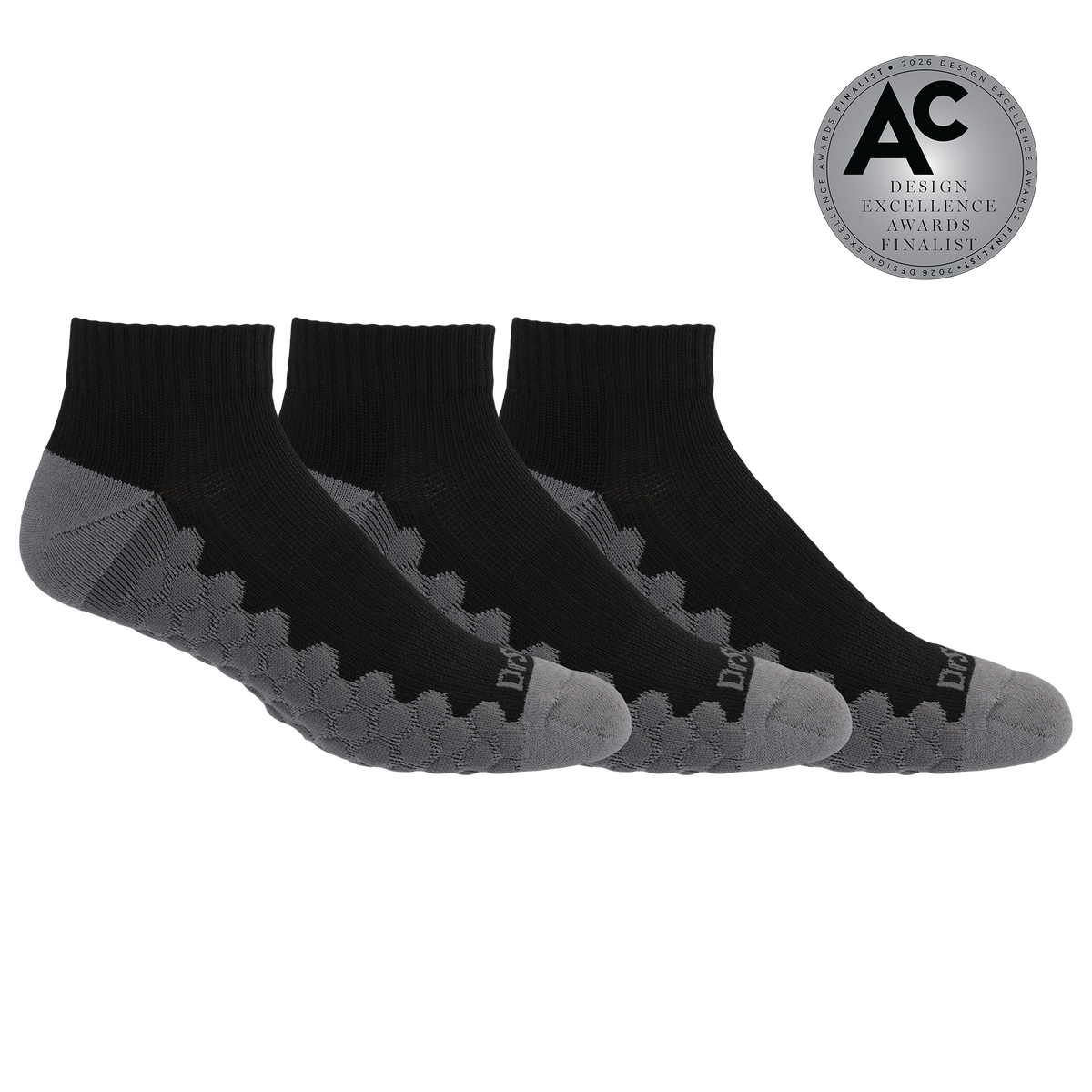 Three low-cut athletic socks in black and gray, arranged in a fan shape on a white background, with a silver circular award badge in the top right corner.