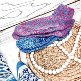 Stack of colorful knitted socks on a woven mat with beads