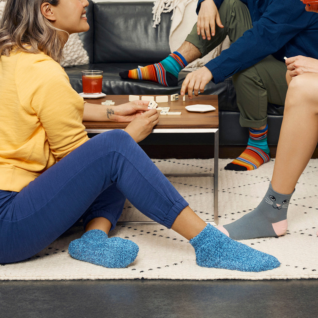 People sitting on a couch wearing colorful socks with a focus on their feet.