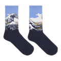 A pair of crew socks featuring a graphic print of Katsushika Hokusai's Great Wave off Kanagawa. The lower half of the socks is a solid dark navy blue, while the upper half features the wave illustration with a light blue sky, white foam, and a tan mountain range.