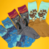 Four pairs of novelty socks featuring famous art prints, arranged in a fan shape on a bright yellow background. The designs include Edvard Munch's The Scream in gray and magenta, Van Gogh's Starry Night in blue, Van Gogh's Sunflowers in light blue, and Van Gogh's Sunflowers in brown.