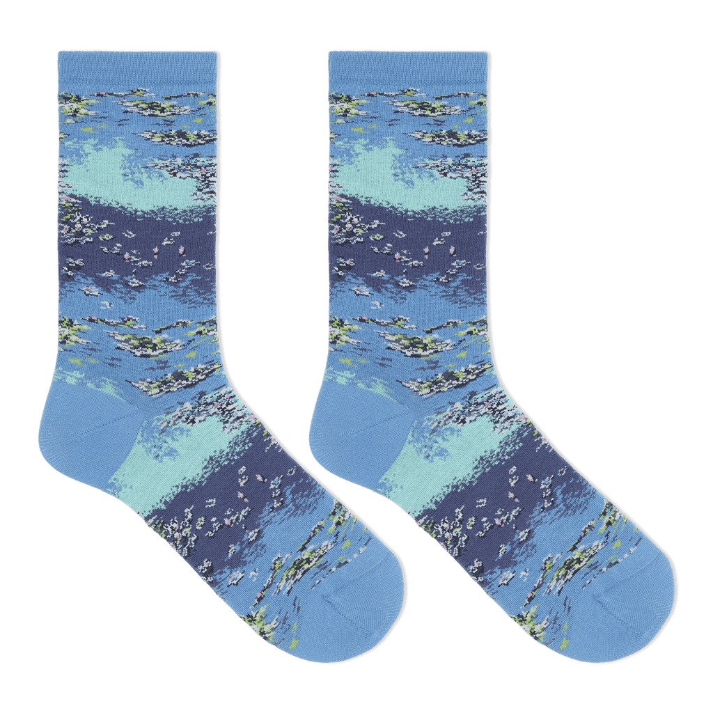 A pair of crew socks with a detailed watercolor-style print of a lake or river scene, featuring blue and light teal water, white ripples, and green reeds, displayed against a solid white background.