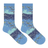 A pair of crew socks with a detailed watercolor-style print of a lake or river scene, featuring blue and light teal water, white ripples, and green reeds, displayed against a solid white background. thumbnail