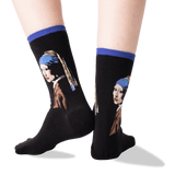 A pair of black crew socks with blue ribbed cuffs, featuring a printed portrait of Vermeer's Girl with a Pearl Necklace on the sides, shown on a person's feet against a white background. thumbnail