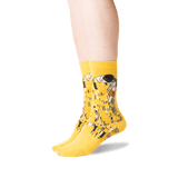 A pair of bright yellow crew socks with a detailed art print of Gustav Klimt's 'The Kiss' on the sides, shown on a person's feet against a plain white background. thumbnail