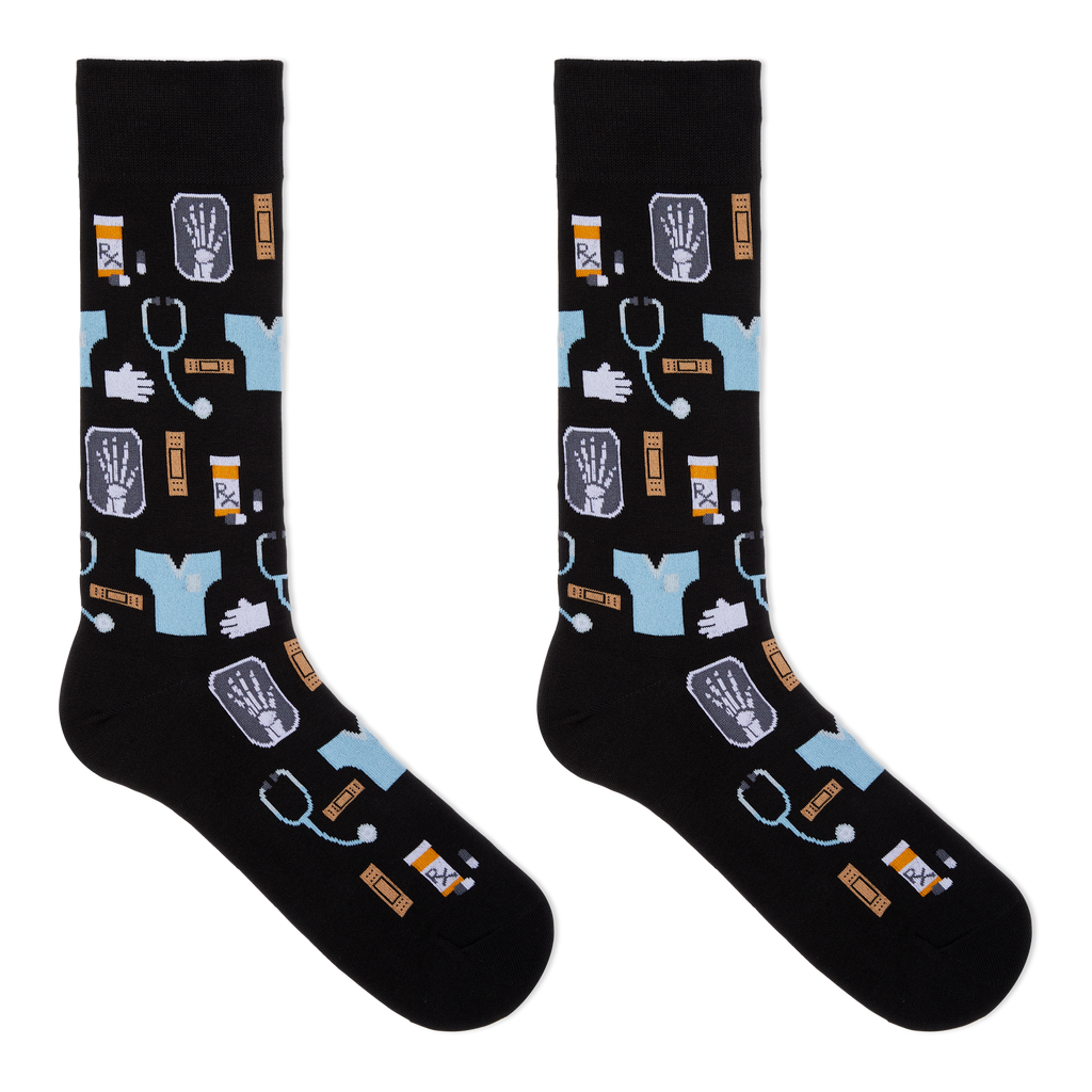 A pair of black crew socks with a medical-themed pattern featuring light blue scrubs, stethoscopes, X-ray images, pills, and hands, displayed against a solid white background.