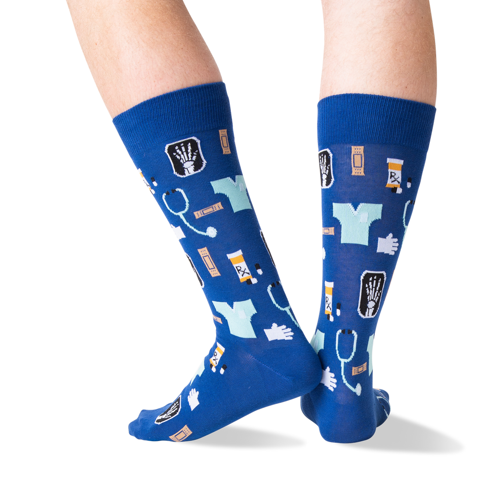 A pair of blue crew socks with a medical-themed pattern, worn on a person's legs against a plain white background.