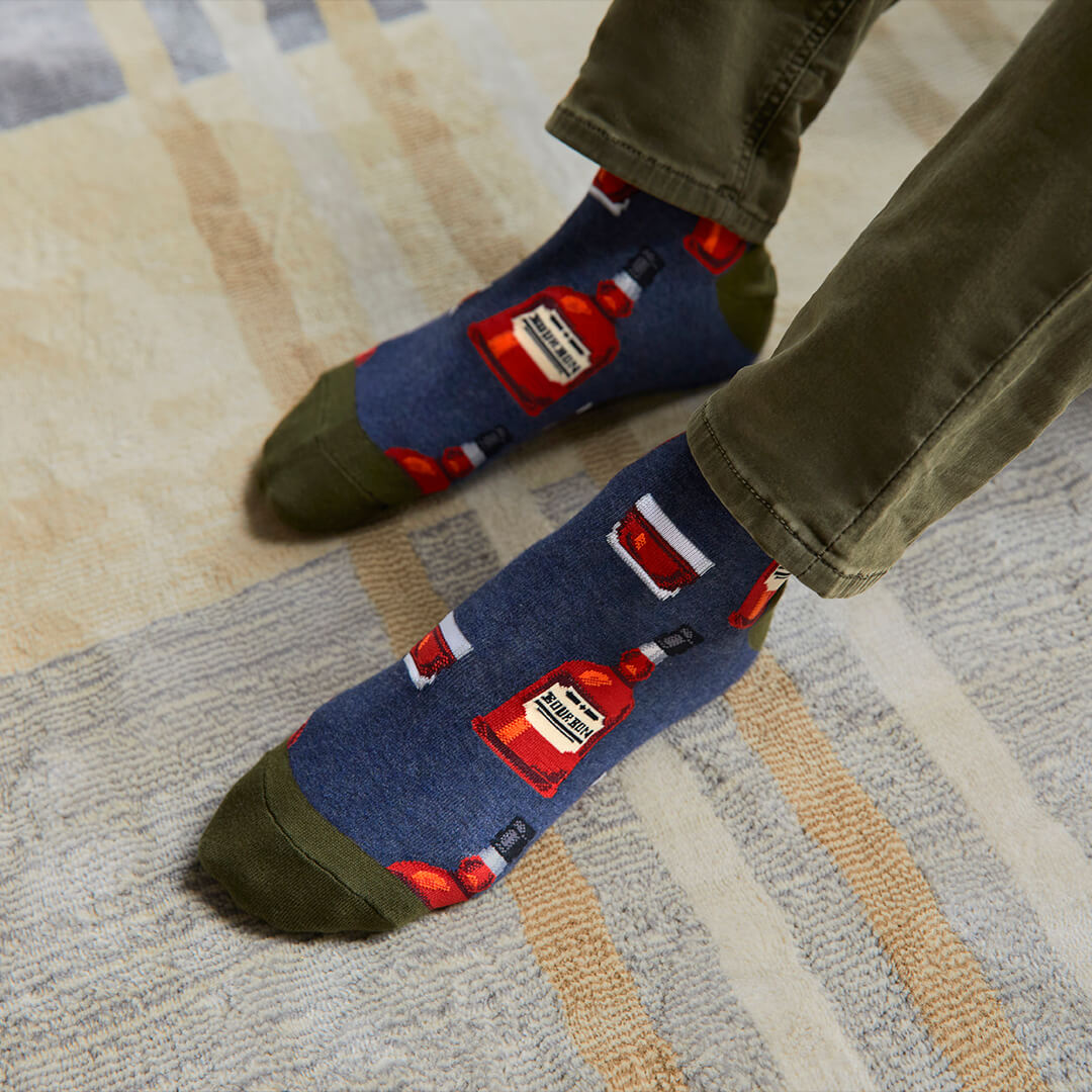 Person wearing socks with bottle designs on a carpeted floor