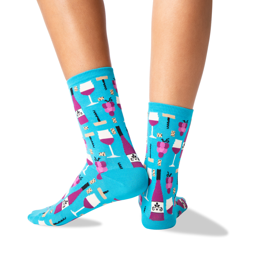 A pair of bright turquoise crew socks with a repeating pattern of wine bottles, wine glasses, and corkscrews, shown on a model's feet against a white background.