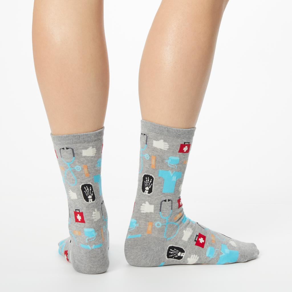 A pair of women's crew socks with a medical supplies print including images of a stethoscope, pills, and a hospital badge.