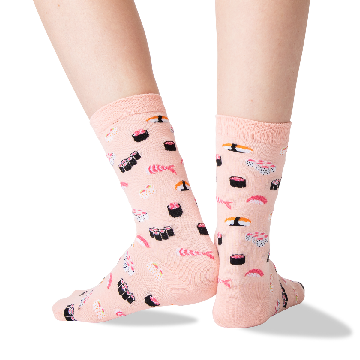 A pair of light pink crew socks with a sushi print, shown on a person's feet against a clean white background.
