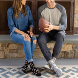 Man and woman sitting on a stone ledge with a football, wearing patterned socks.