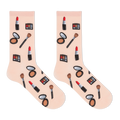A pair of light pink crew socks with a repeating pattern of various makeup items, including lipstick, eyeshadow palettes, brushes, and compacts, displayed on a clean white background.