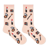 A pair of light pink crew socks with a repeating pattern of various makeup items, including lipstick, eyeshadow palettes, brushes, and compacts, displayed on a clean white background. thumbnail