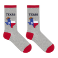 A pair of heather gray crew socks with red cuffs, heels, and toes. Each sock features a graphic of the state of Texas filled with the Texas flag and a cowboy hat, with the word 'TEXAS' printed above in dark navy.