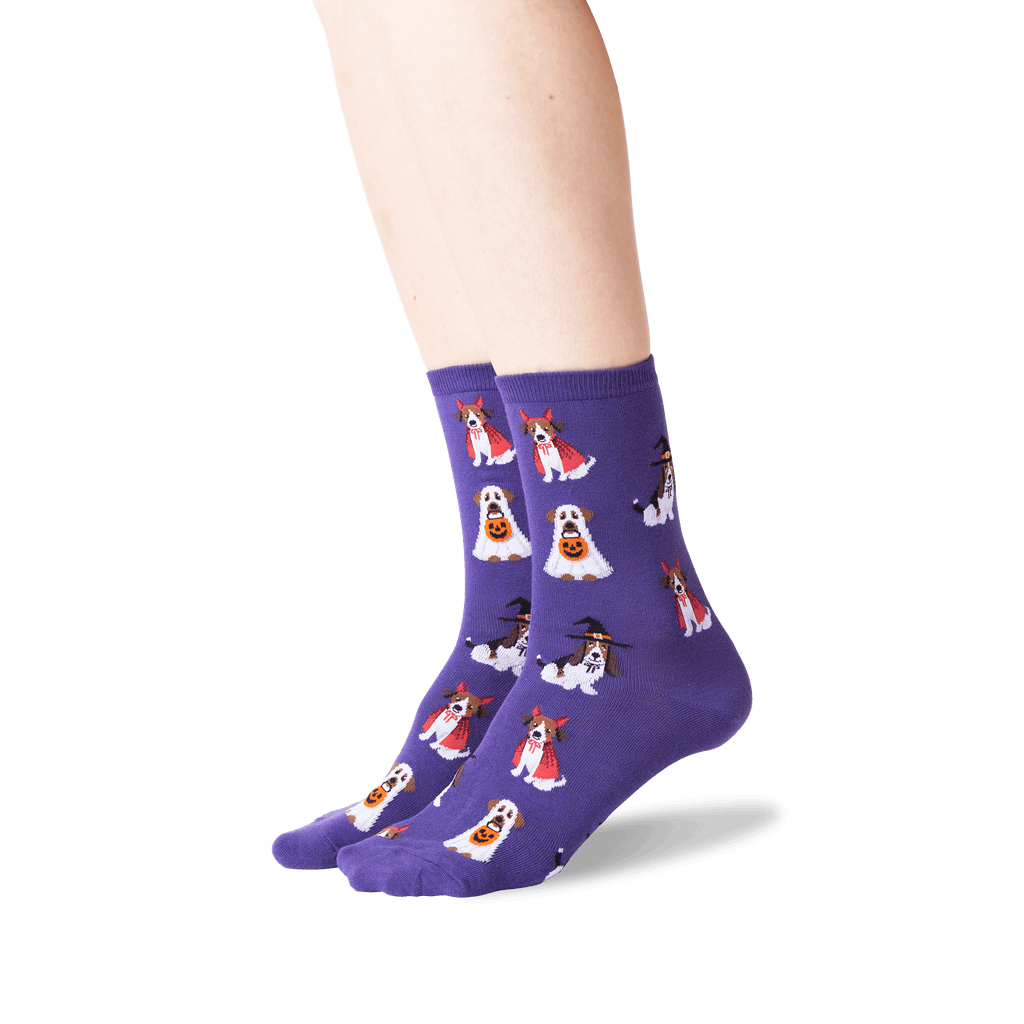 A pair of purple crew socks with a repeating pattern of cartoon dogs dressed as ghosts and witches, shown on a person's feet against a white background.