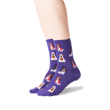 A pair of purple crew socks with a repeating pattern of cartoon dogs dressed as ghosts and witches, shown on a person's feet against a white background.