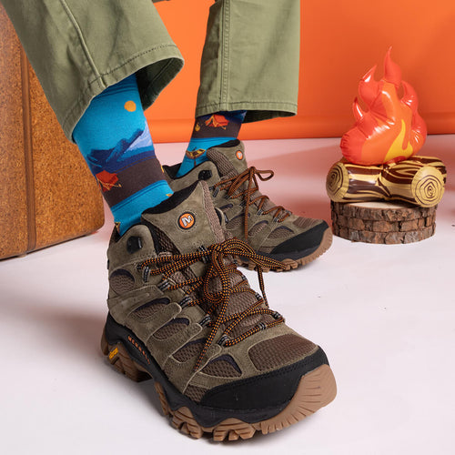 Brown hiking boots with blue socks worn, against an orange and white background.