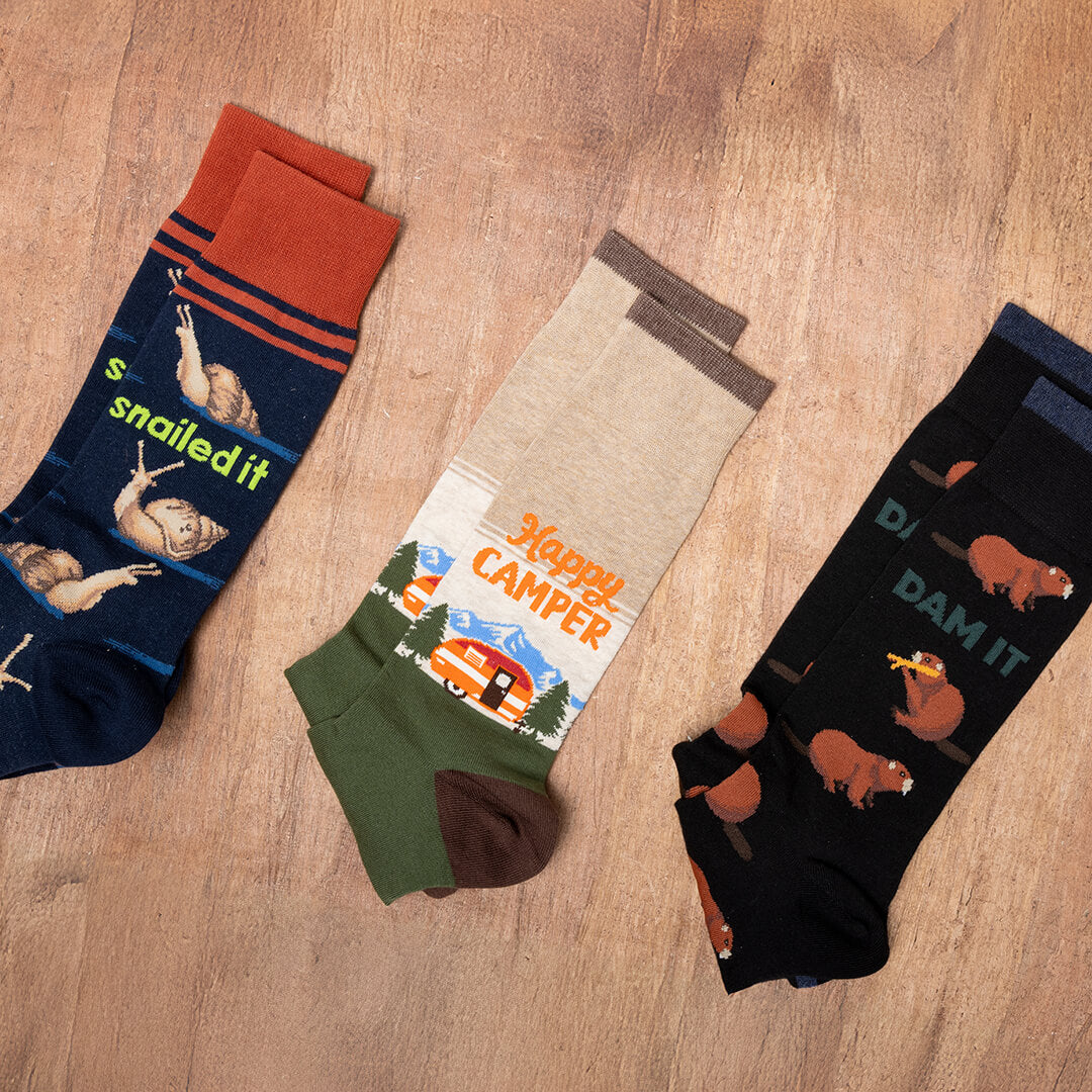 Three pairs of socks with humorous designs on a wooden surface