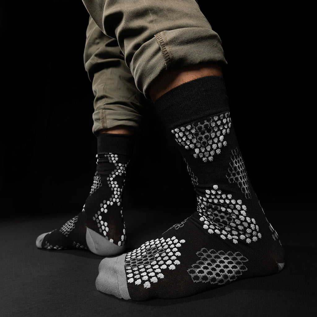 Black socks with white pattern worn by a person on a black background