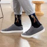 A person wearing black crew socks with a graphic print of 'Girl With a Pearl Earring' and gray knit sneakers, standing on a polished wood floor. thumbnail