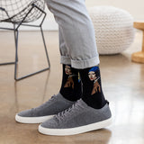 A person wearing black crew socks with a graphic print of 'Girl With a Pearl Earring' and gray knit sneakers, standing on a polished wood floor. thumbnail