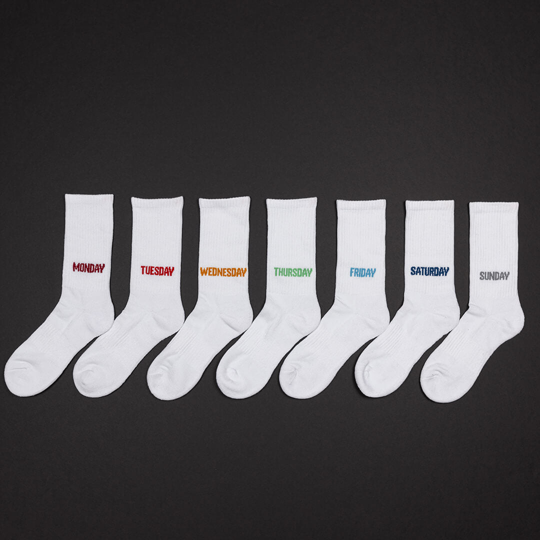 Set of white socks with days of the week text on a black background