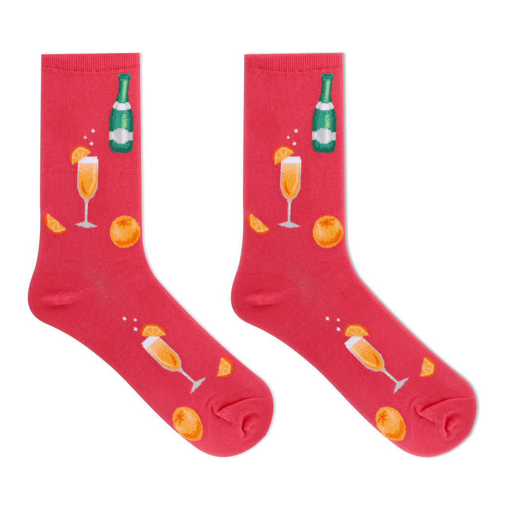 A pair of bright pink crew socks featuring a festive champagne-themed print with orange slices, champagne glasses, and a green champagne bottle, displayed against a solid white background.