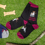 Black socks with dog illustrations and 'branch manager' text on a grass background with dog bones and a branch. thumbnail