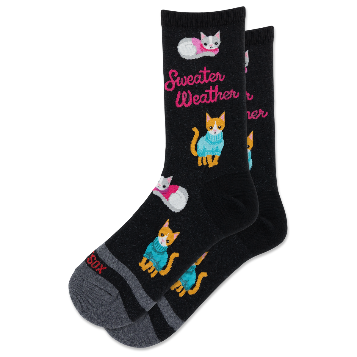 A pair of black crew socks with a cozy pattern of orange and white kittens wearing blue and pink sweaters, alongside the pink text 'Sweater Weather'. The toes and heels are gray, and the word 'SOX' is printed on the toe.