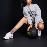 Person wearing a gray sweatshirt and white sneakers with a basketball on a black background thumbnail