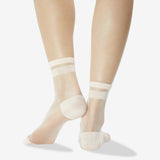 A pair of sheer nude ankle socks worn on a model's feet, shown from the back against a clean white background. thumbnail