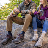 Two people sitting on rocks outdoors, wearing hiking shoes and enjoying a snack.