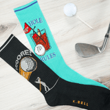 Golf-themed socks with humorous design on a wooden surface with golf club and ball. thumbnail