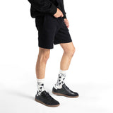 Person wearing black shorts, black sneakers, and white socks with palm tree design on a white background