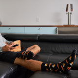 Person sitting on a couch wearing socks with bear designs, holding a remote control.