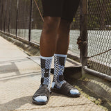 Person wearing black and white striped socks with sandals on a sidewalk.