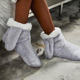 Gray fuzzy bunny slippers with white trim worn by a person on a concrete floor.