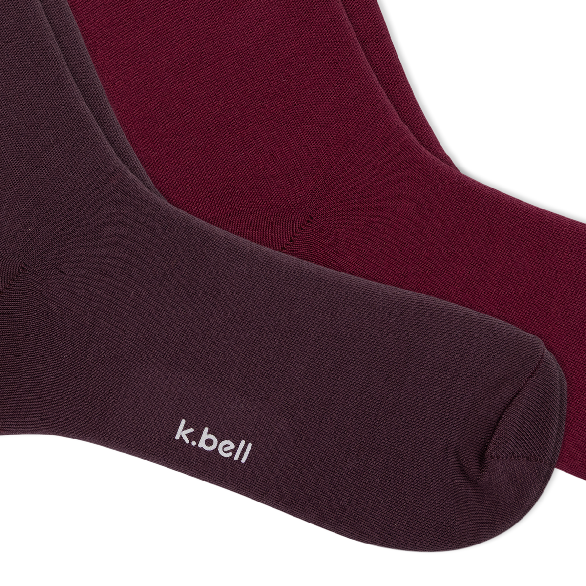 Two pairs of crew socks from k.bell, fanned out on a white background, with three tiers of ruffled colors from dark plum to burgundy, maroon, and dusty pink.