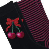 Two pairs of black crew socks arranged diagonally. The front sock features a red bow and two pink cherries with green stems, while the back pair has thin horizontal pink stripes. thumbnail