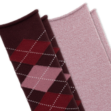 Two pairs of knit socks arranged diagonally on a white background. The front pair is dark burgundy with an argyle pattern in red, pink, and white dotted lines. The back pair is a solid light heathered pink. thumbnail
