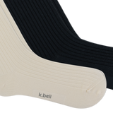 Two ribbed crew socks shown overlapping on a white background, with one sock in warm off-white/cream and the other in black. The cream sock has the brand name 'k.bell' on the foot. thumbnail