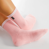 Pink socks with white stripes worn by a person on a light gray background
