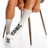 White socks with 'Iconic' text worn by a person sitting on a chair.