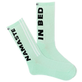 A pair of mint green sports crew socks with the text 'NAMASTE IN BED' printed on the side, featuring a reflective logo and a striped design with a visible logo on the calf area.