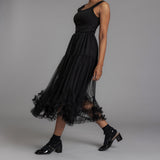 Woman wearing a black dress with sheer overlay on a gray background thumbnail