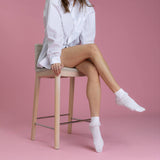 Person sitting on a stool wearing white socks against a pink background thumbnail