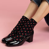 Black shoes with strawberry pattern socks on a pink background thumbnail