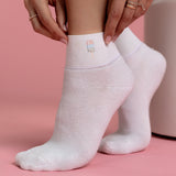 White socks with a small embroidered popsicle on a pink background thumbnail
