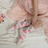 Person wearing floral socks with a pink dress on a textured surface. thumbnail